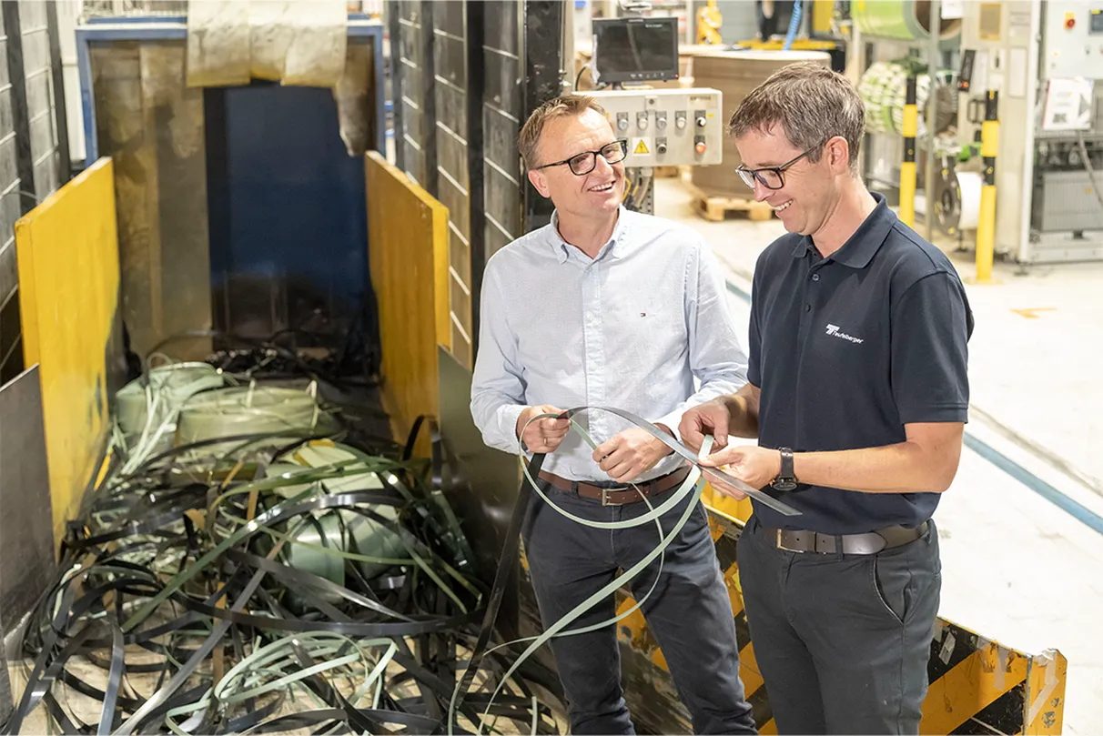Two men discussing fiber and wire strapping solutions in an industrial setting, emphasizing safety and quality in their products.