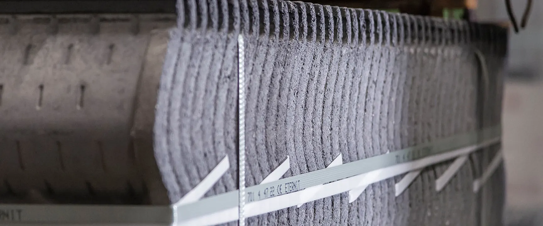 Stacked fiber cement corrugated sheets secured with metal straps – durable roofing materials in industrial packaging, ideal for long-lasting roof solutions.