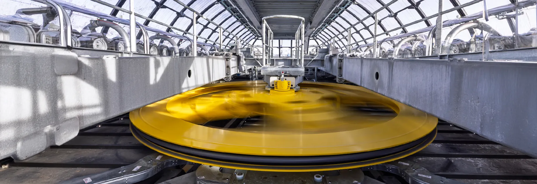 Industrial machine with a spinning yellow wheel inside a modern facility, showcasing innovation and precision.