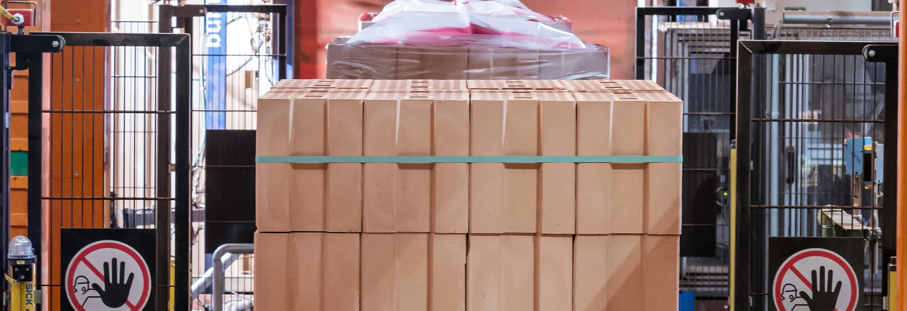 Stack of beige blocks, neatly arranged and secured with a blue strapping band; industrial background with metal bars and machinery.