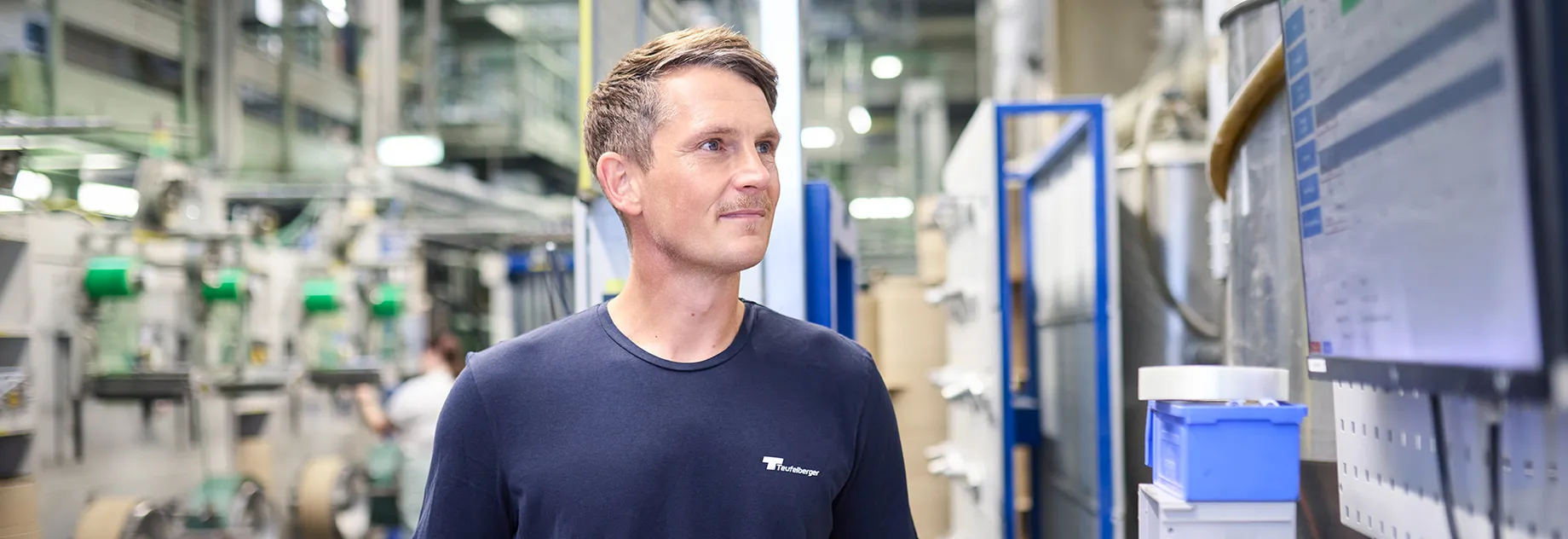 Employee monitoring production data on a screen and inspecting strapping in the manufacturing area