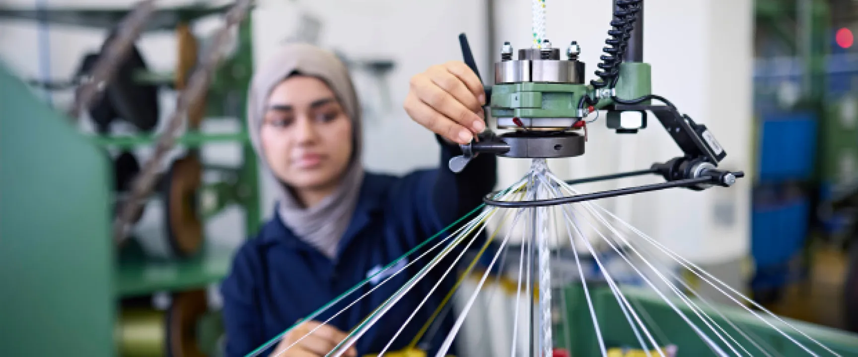Person operating machinery to weave fiber ropes in an industrial setting, focusing on precision and quality.