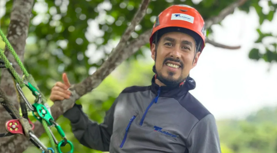 Science Ambassador Felipe standing on a branch, secured with a Teufelberger hipSTAR Flex Lanyard. Giving a thumbs up.