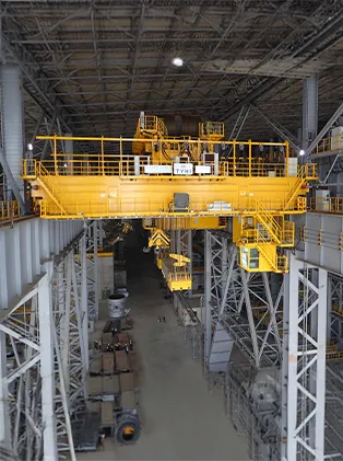 Interior of an industrial hall with a large yellow overhead crane and machinery – efficient lifting and handling technology for industrial applications.