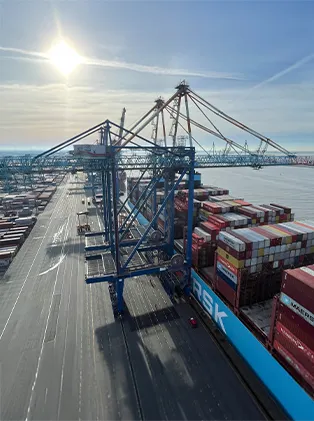 Large shipping port with container ship, cranes, and stacked cargo containers under bright sunlight – efficient logistics solutions for global supply chains.