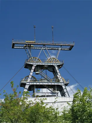 Metal mining headframe with platforms and antennas against a clear blue sky – representing modern mining technology and industrial infrastructure.