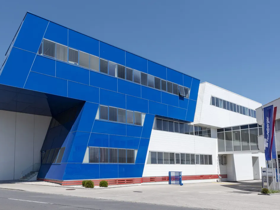 Modern building with bold blue and white geometric design, large windows, and a clear sky background.