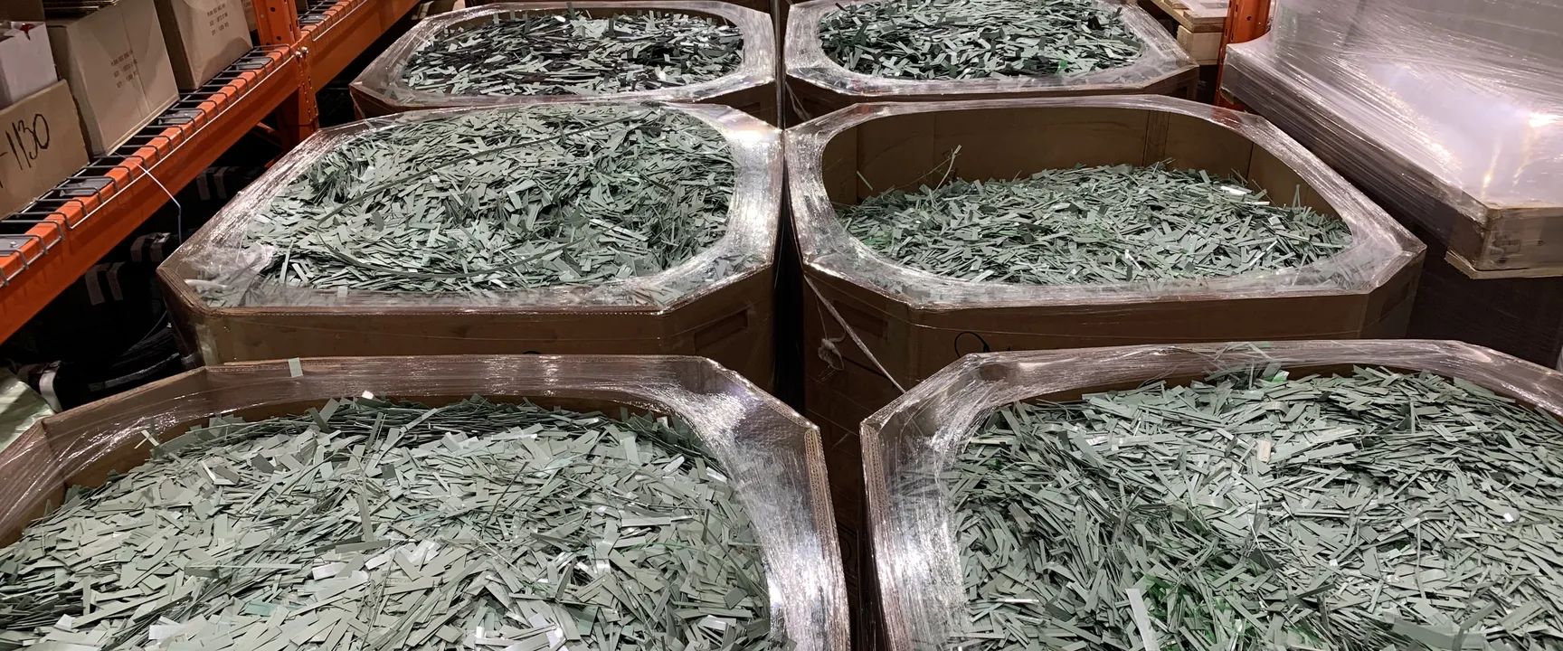Large boxes in a warehouse filled with shredded green material.