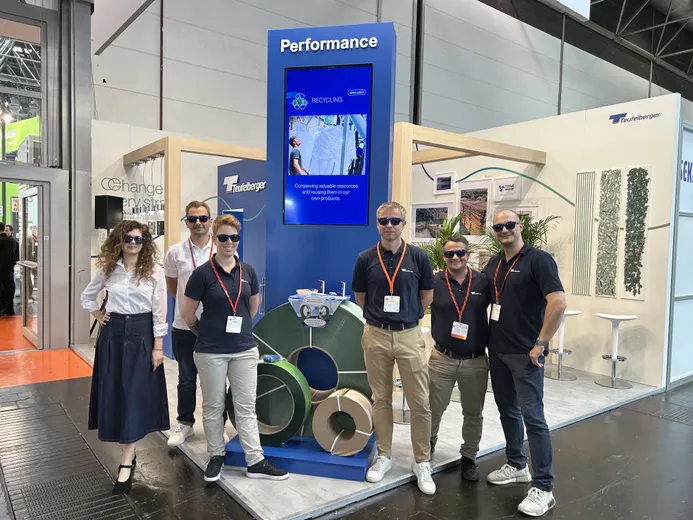 Team at exhibition booth showcasing strapping, with a performance display, emphasizing quality and innovation.