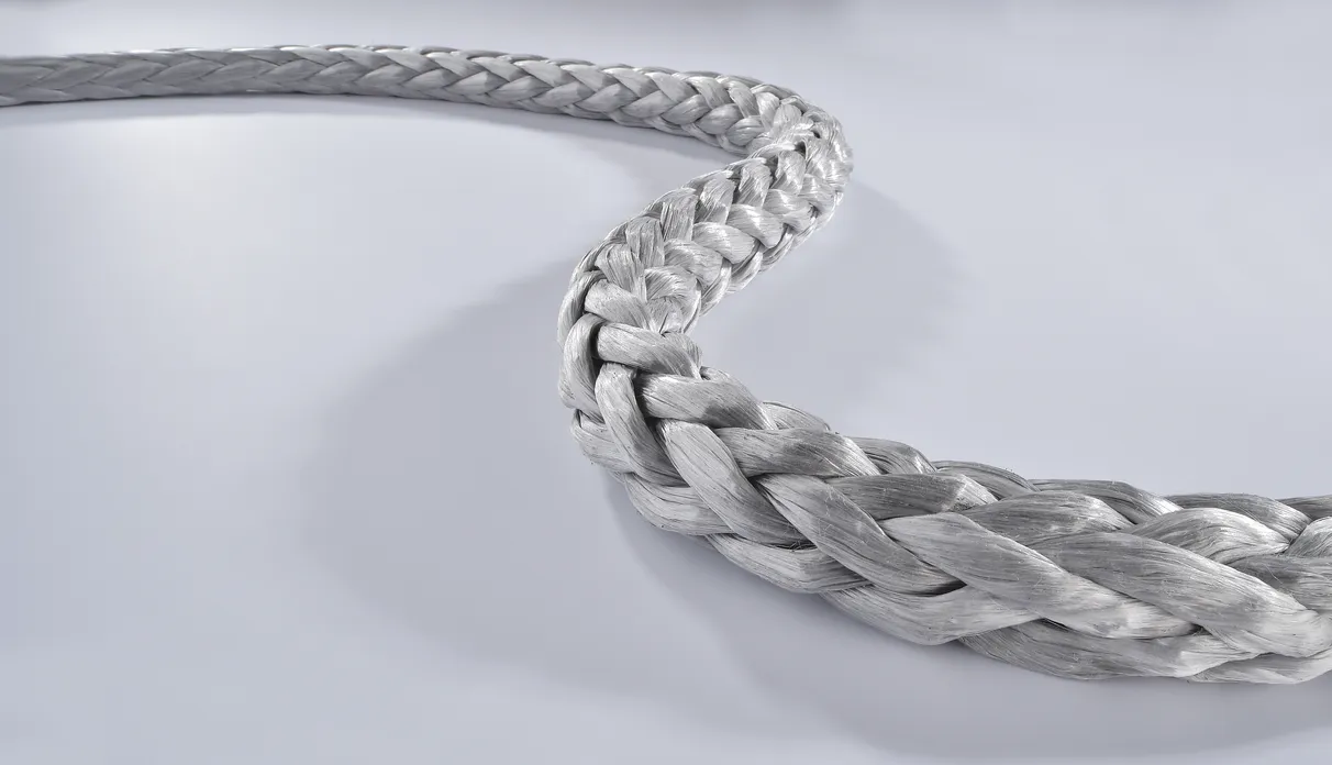 Close-up view of a thick, silver-gray braided rope with a smooth, glossy texture, lying in a curved shape on a light gray surface.