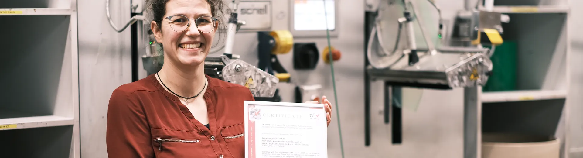 Person holding a certificate within a production area of PET strapping