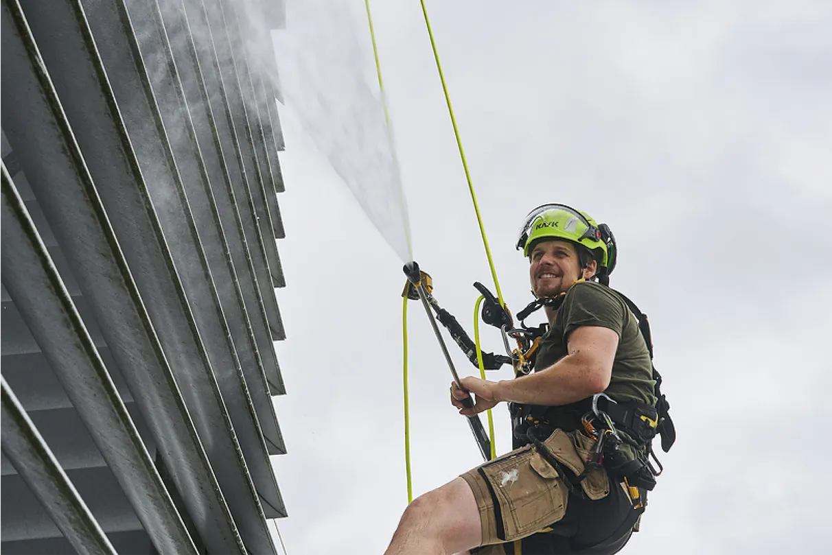 Worker during his job at height cleaning a construct on top of a building with a high pressure water