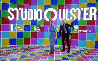 Chancellor Rachel Reeves and Studio Ulster CEO Declan Keeney on the CoSTAR Screen Lab stage with the LED screen displaying the Studio Ulster, Ulster University, Belfast Region City Deal, Northern Ireland Executive, and UK Government logos.
