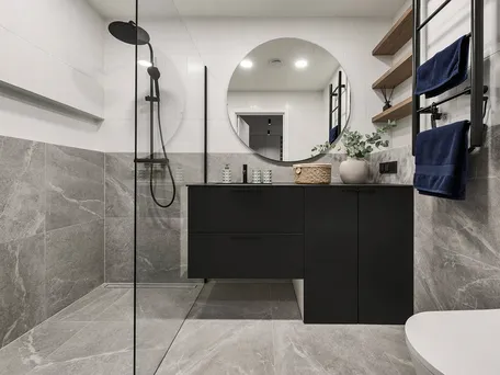 Badkamer met grijze wandtegels, blauwe handdoeken en accessoires