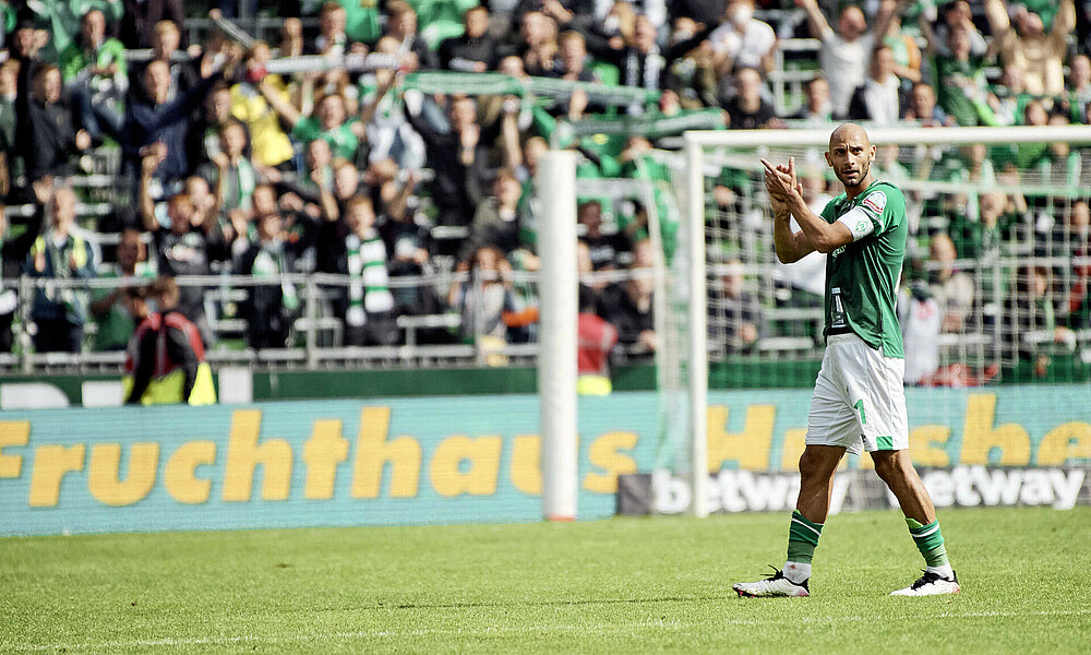 Ömer Toprak klatscht im Weder-Trikot in die Hände. 