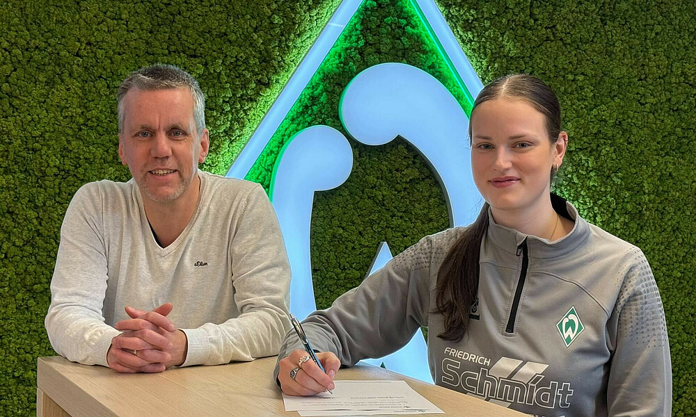 null Martin Lange und Alina Defayay vor der Werder-Raute