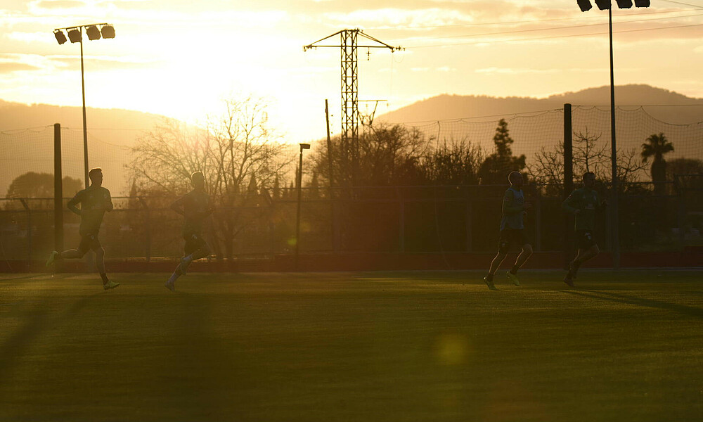 null Profis des SV Werder Bremen laufen bei Sonnenuntergang auf einem Trainingsplatz.