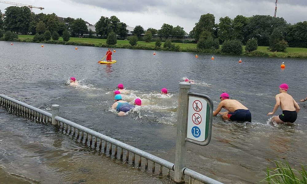 Menschen springen beim Werdersee ins Wasser und schwimmen.