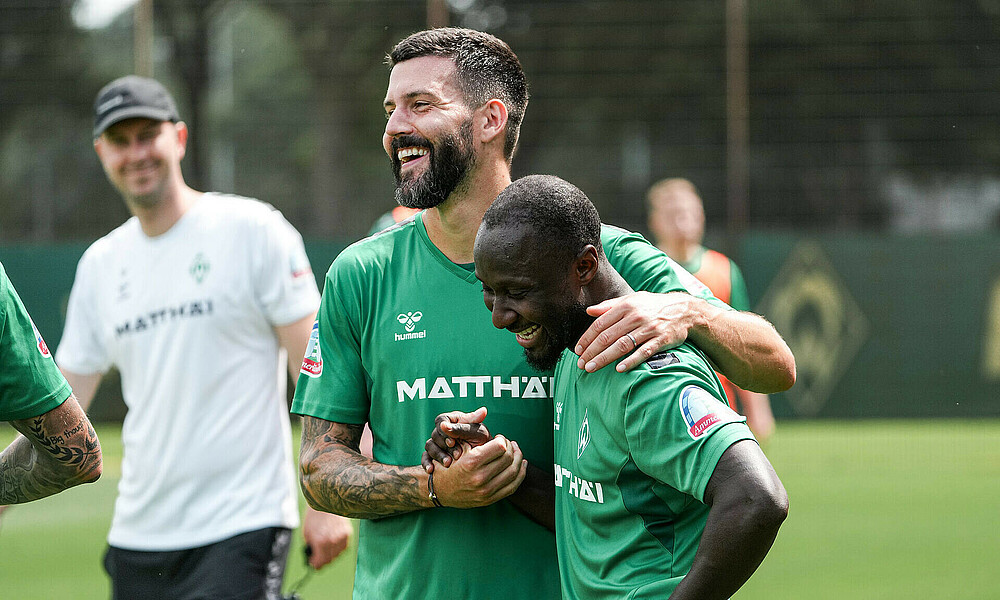 Naby Keita und Tony Jung lachen und schütteln die Hände