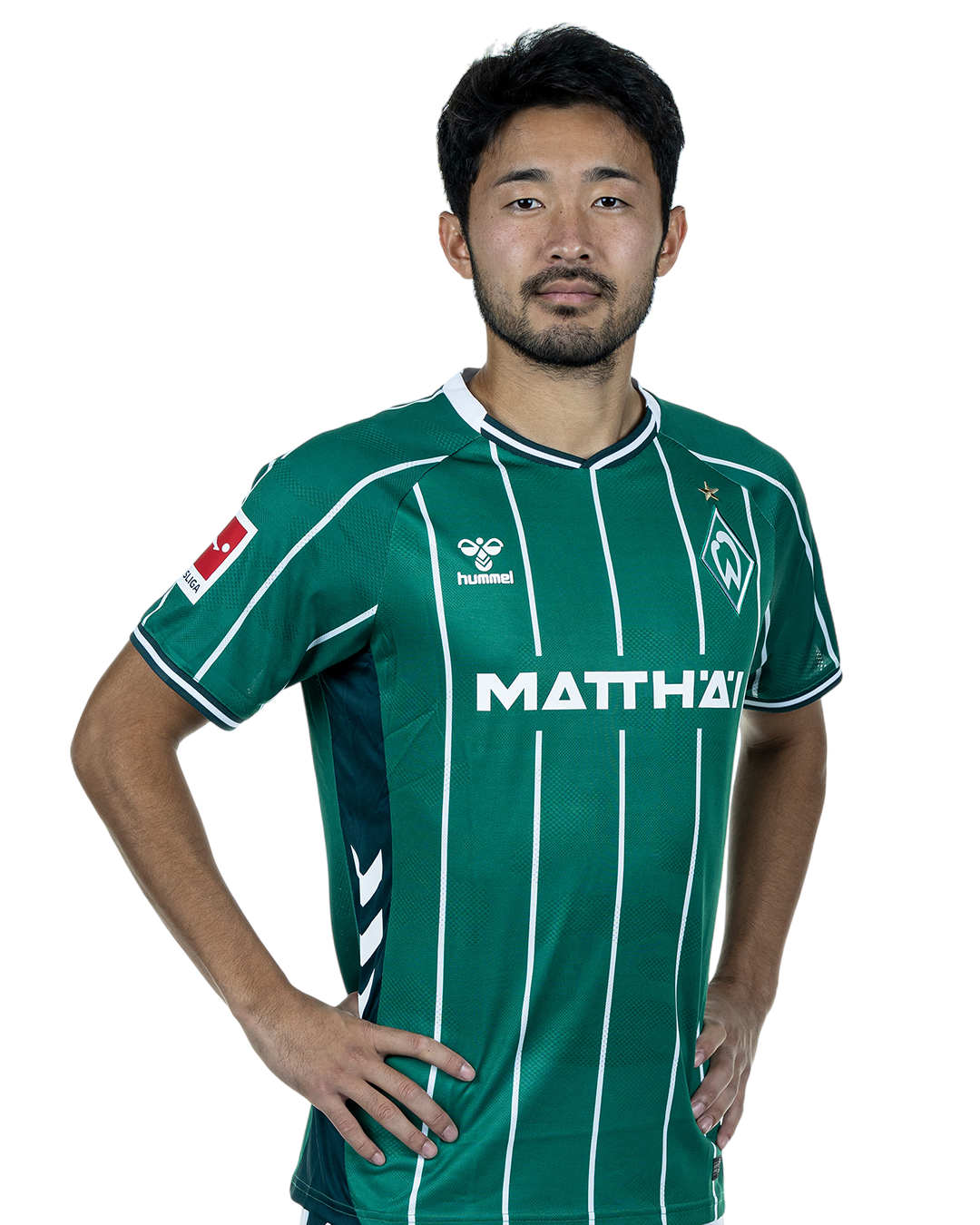 Yukinara Sugawara in einem grün-weiß gestreiften Trikot mit der Aufschrift „MATTHÄI“ auf der Vorderseite steht mit den Händen in den Hüften da und schaut nach vorne.