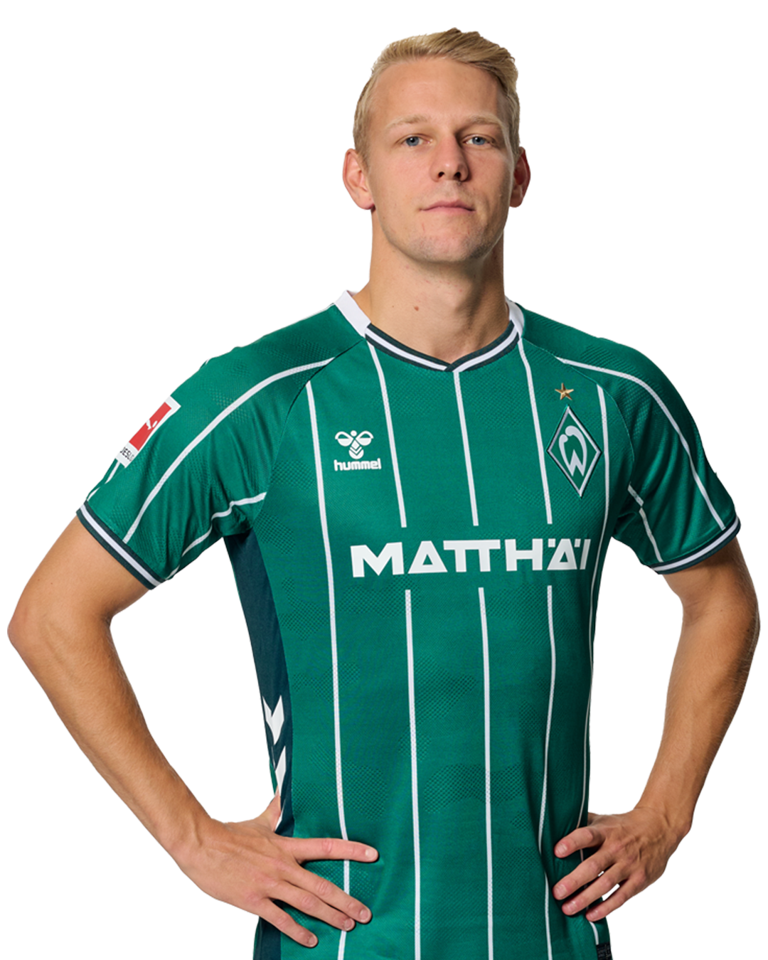 Marco Grüll in einem grün-weiß gestreiften Trikot mit der Aufschrift „MATTHÄI“ auf der Vorderseite steht mit den Händen in den Hüften da und schaut nach vorne.