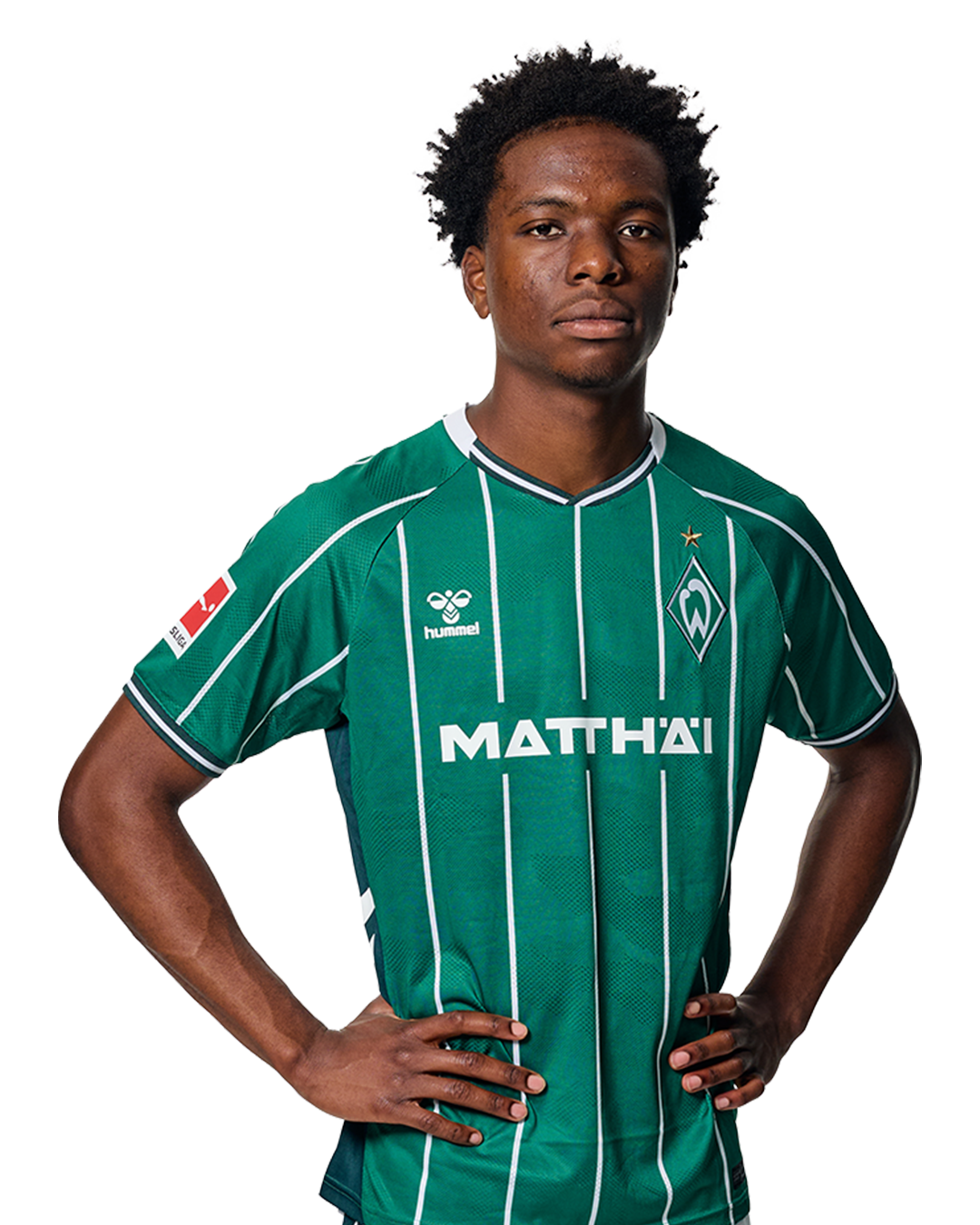 Wesley Adeh in einem grün-weiß gestreiften Trikot mit der Aufschrift „MATTHÄI“ auf der Vorderseite steht mit den Händen in den Hüften da und schaut nach vorne.