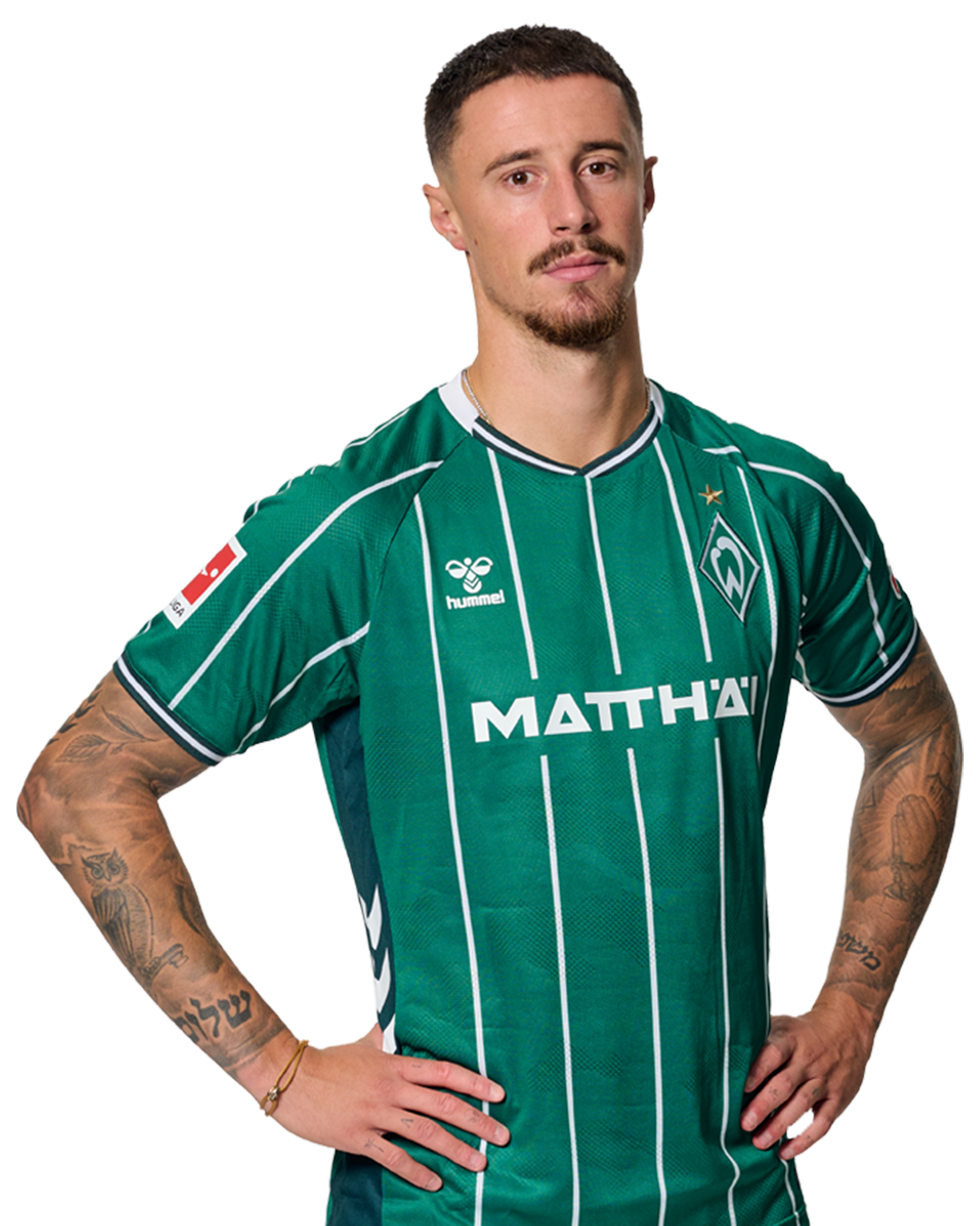 Marco Friedl in einem grün-weiß gestreiften Trikot mit der Aufschrift „MATTHÄI“ auf der Vorderseite steht mit den Händen in den Hüften da und schaut nach vorne.