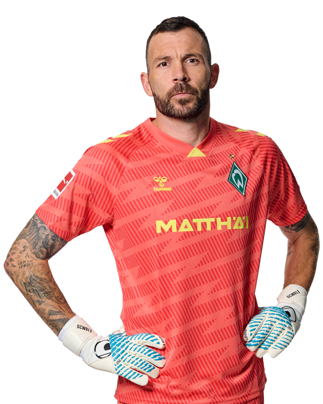 Markus Kolke im roten Torwarttrikot mit der Aufschrift "MATTHÄI" und Handschuhen, der mit den Händen in den Hüften steht und nach vorne schaut. Seine Arme sind tätowiert.