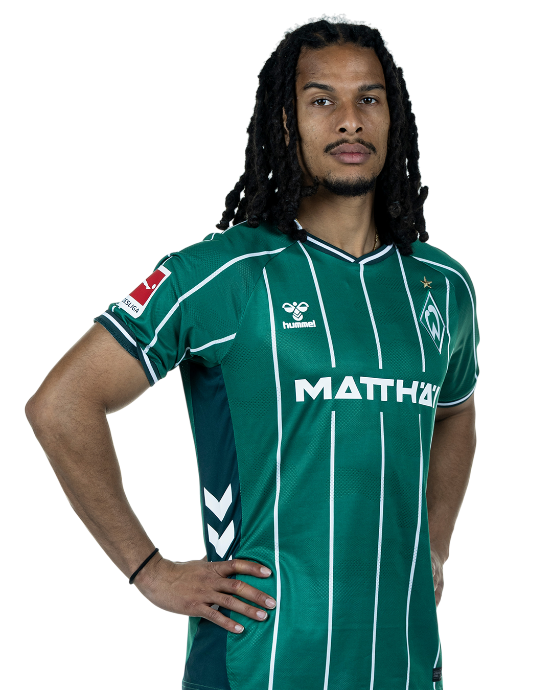 Isaac Schmidt in einem grün-weiß gestreiften Trikot mit der Aufschrift „MATTHÄI“ auf der Vorderseite steht mit den Händen in den Hüften da und schaut nach vorne.