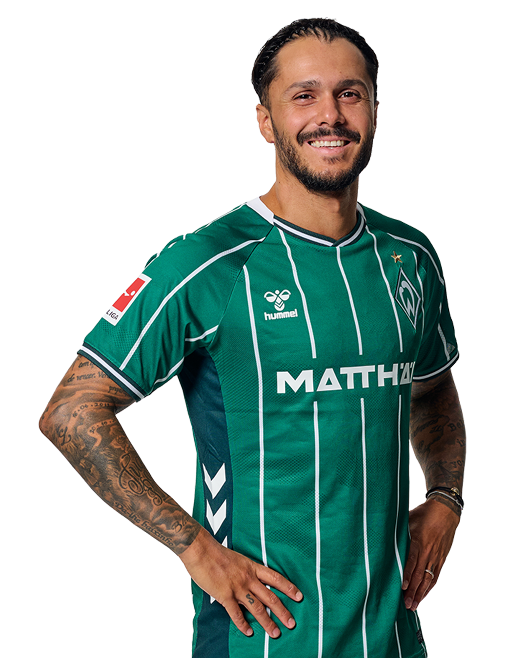 Leonardo Bittencourt in einem grün-weiß gestreiften Trikot mit der Aufschrift „MATTHÄI“ auf der Vorderseite steht mit den Händen in den Hüften da und schaut nach vorne.