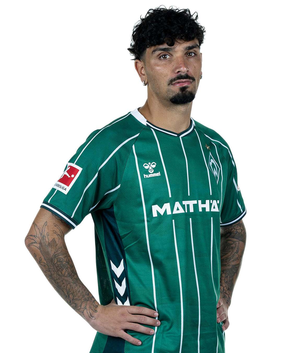 Cameron Puertas in einem grün-weiß gestreiften Trikot mit der Aufschrift „MATTHÄI“ auf der Vorderseite steht mit den Händen in den Hüften da und schaut nach vorne.