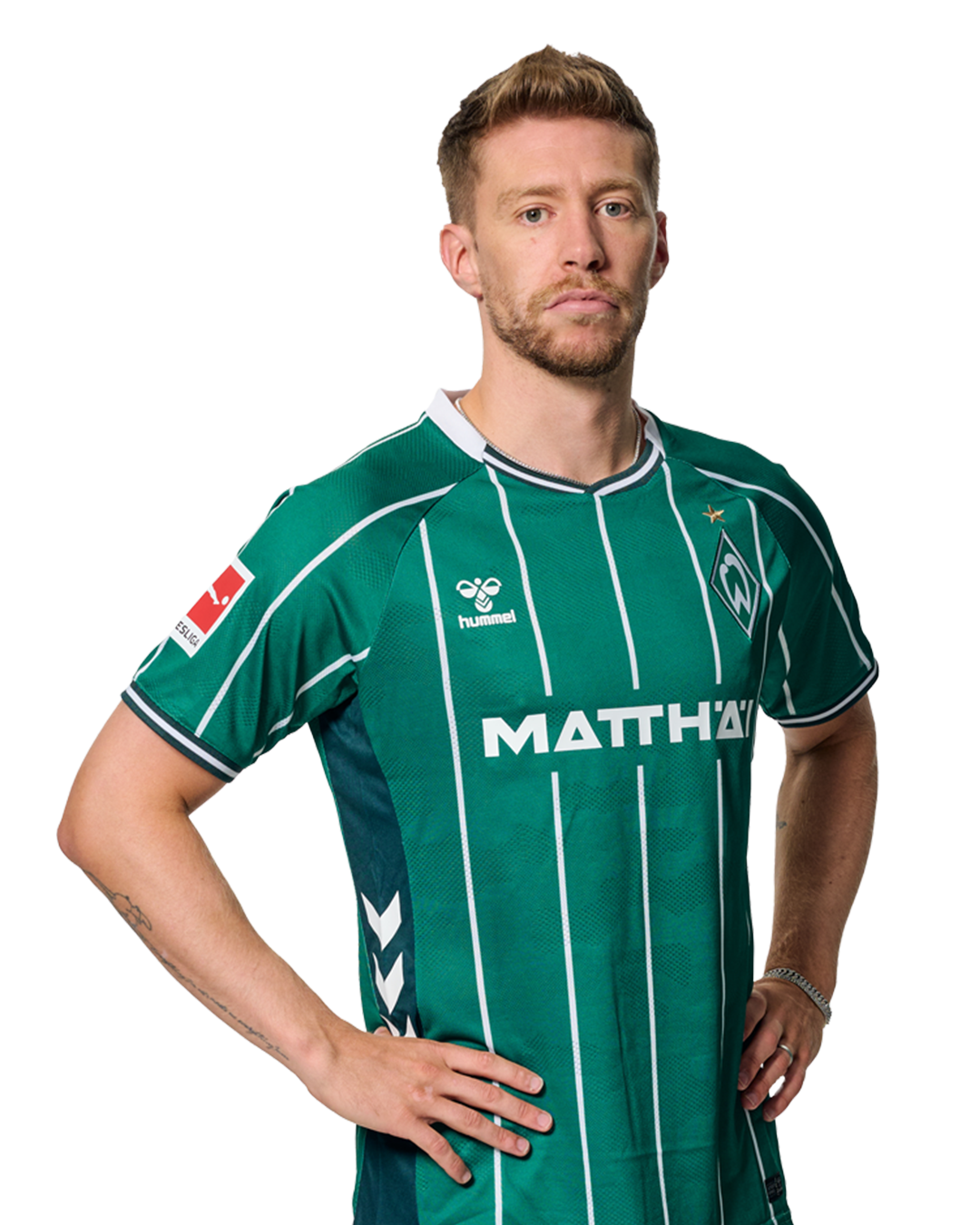 Mitchell Weiser im grün-weiß gestreiften Trikot mit Sponsorenlogos, der mit den Händen in den Hüften dasteht und nach vorne schaut.