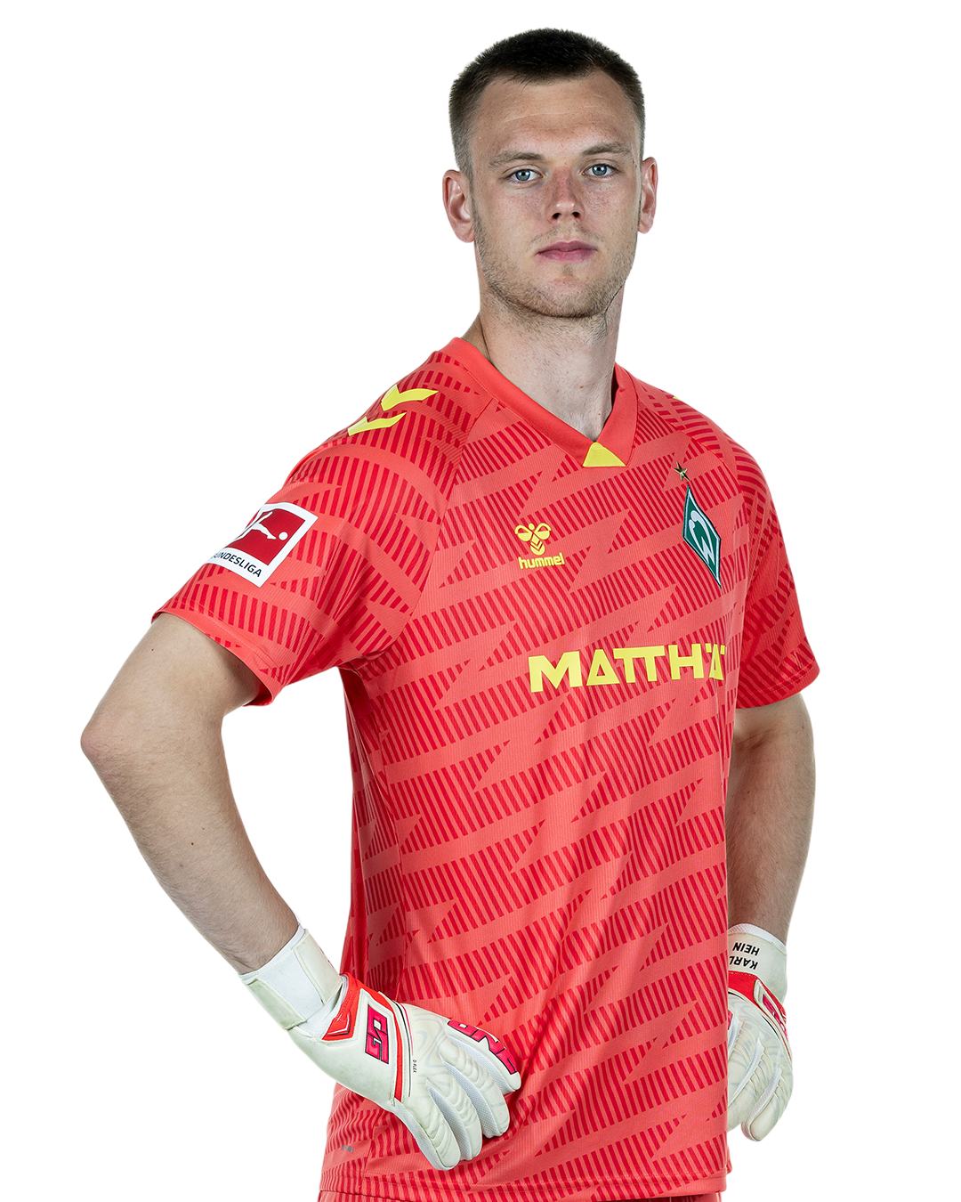 Karl Hein im rotem Trikot mit der Aufschrift "MATTHÄI" und Handschuhen, der selbstbewusst mit den Händen in den Hüften dasteht und nach vorne schaut.