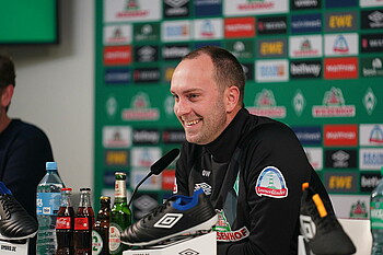 null Ole Werner sitzt auf dem Podium im PK-Raum.