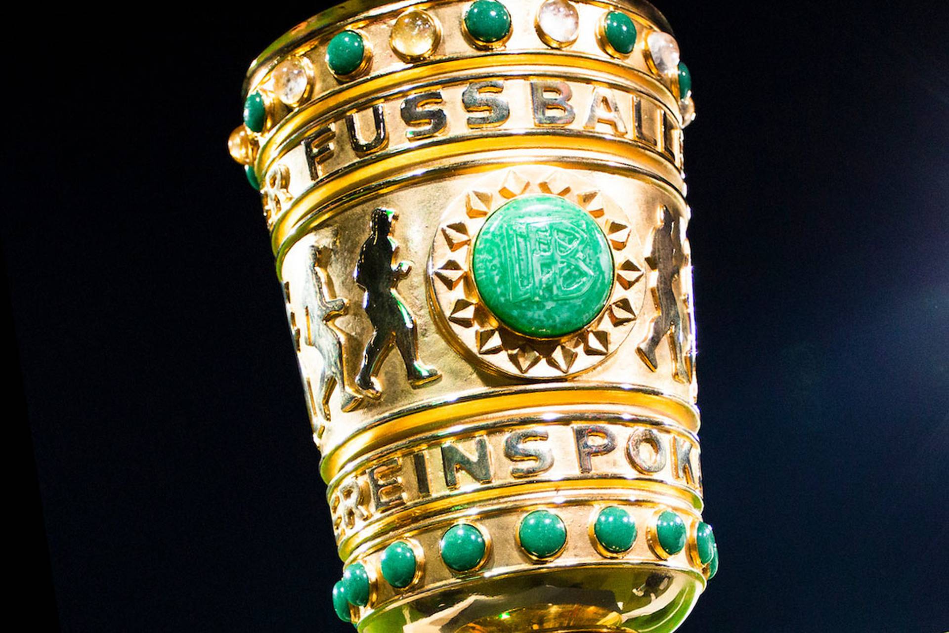 Goldene Trophäe mit grünen Edelsteinen, mit Reliefmuster und der Aufschrift „Fußball“.