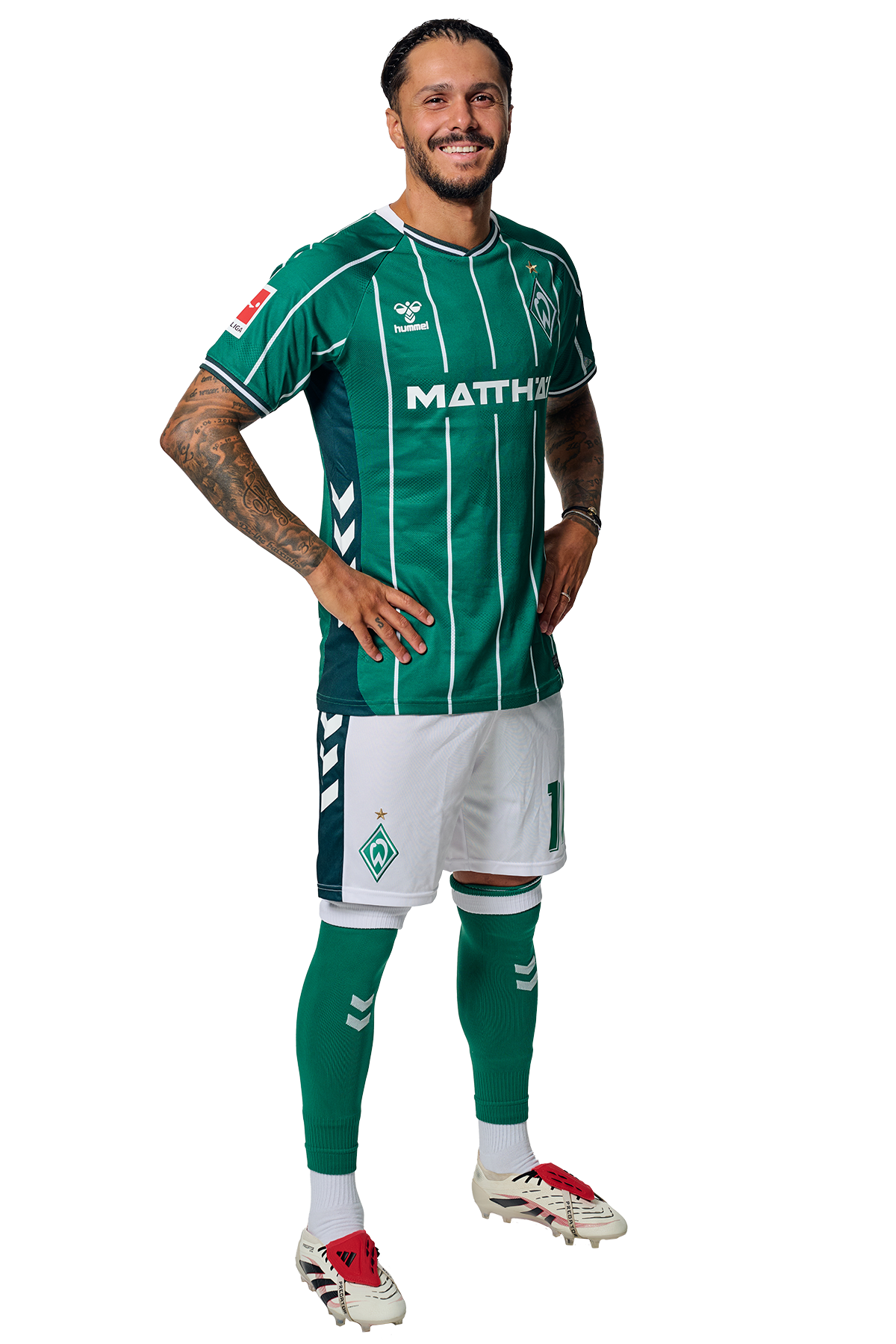 Leonardo Bittencourt in einem grün-weiß gestreiften Trikot mit der Aufschrift „MATTHÄI“ auf der Vorderseite steht mit den Händen in den Hüften da und schaut nach vorne.