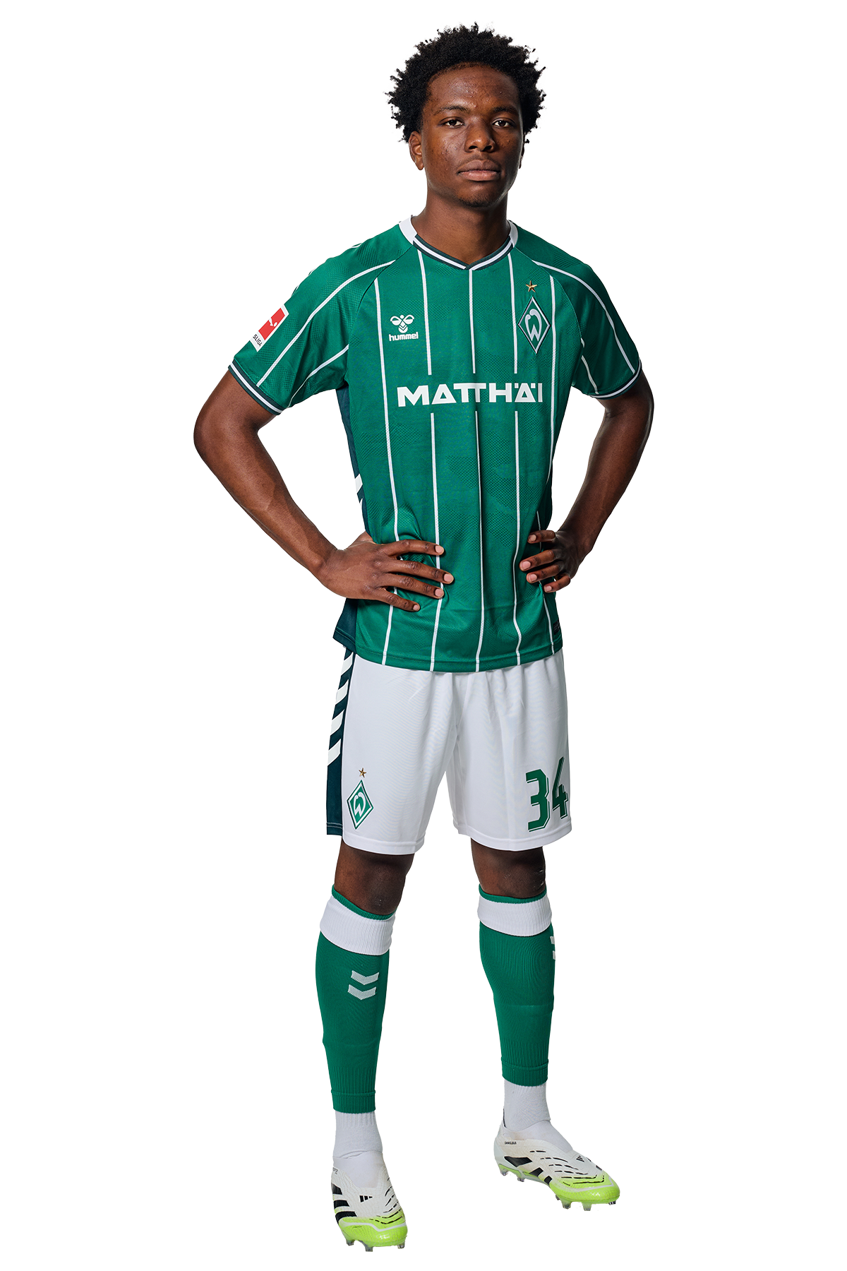 Wesley Adeh in einem grün-weiß gestreiften Trikot mit der Aufschrift „MATTHÄI“ auf der Vorderseite steht mit den Händen in den Hüften da und schaut nach vorne.