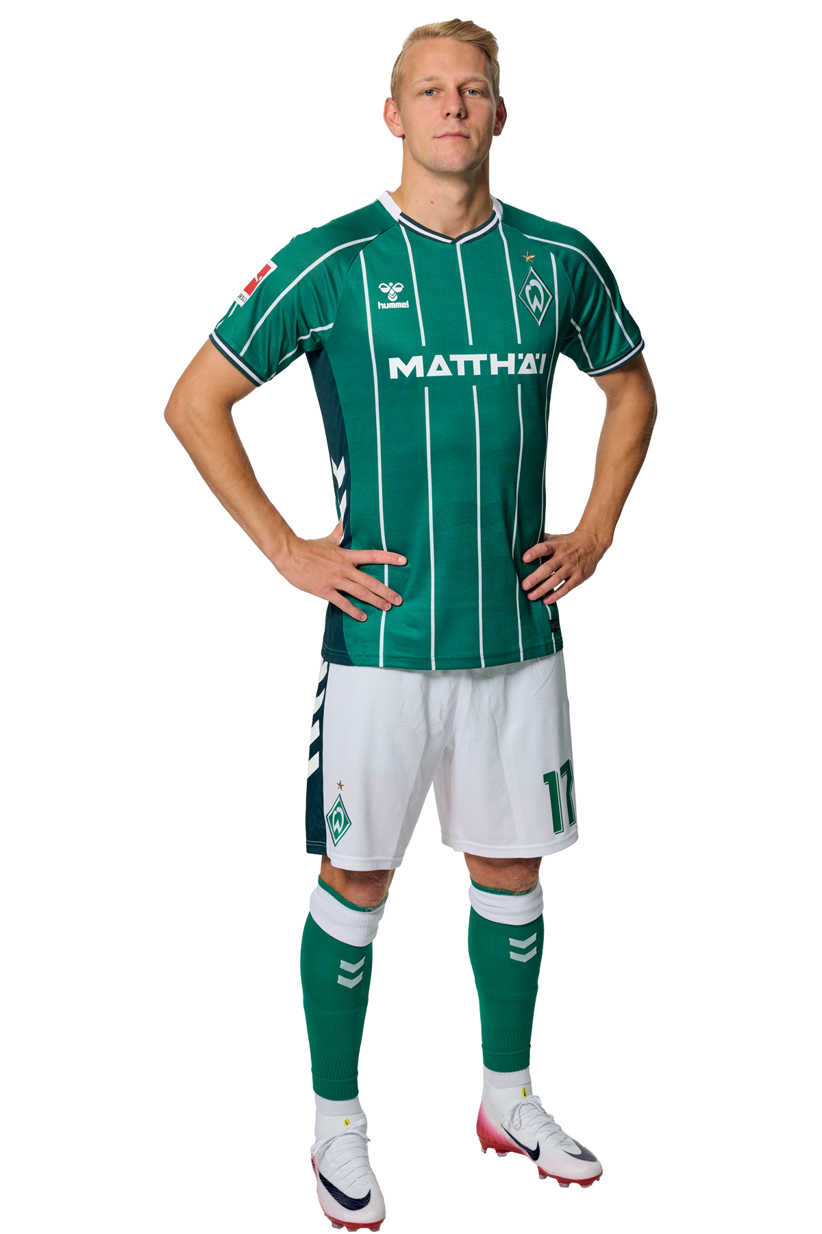 Marco Grüll in einem grün-weiß gestreiften Trikot mit der Aufschrift „MATTHÄI“ auf der Vorderseite steht mit den Händen in den Hüften da und schaut nach vorne.