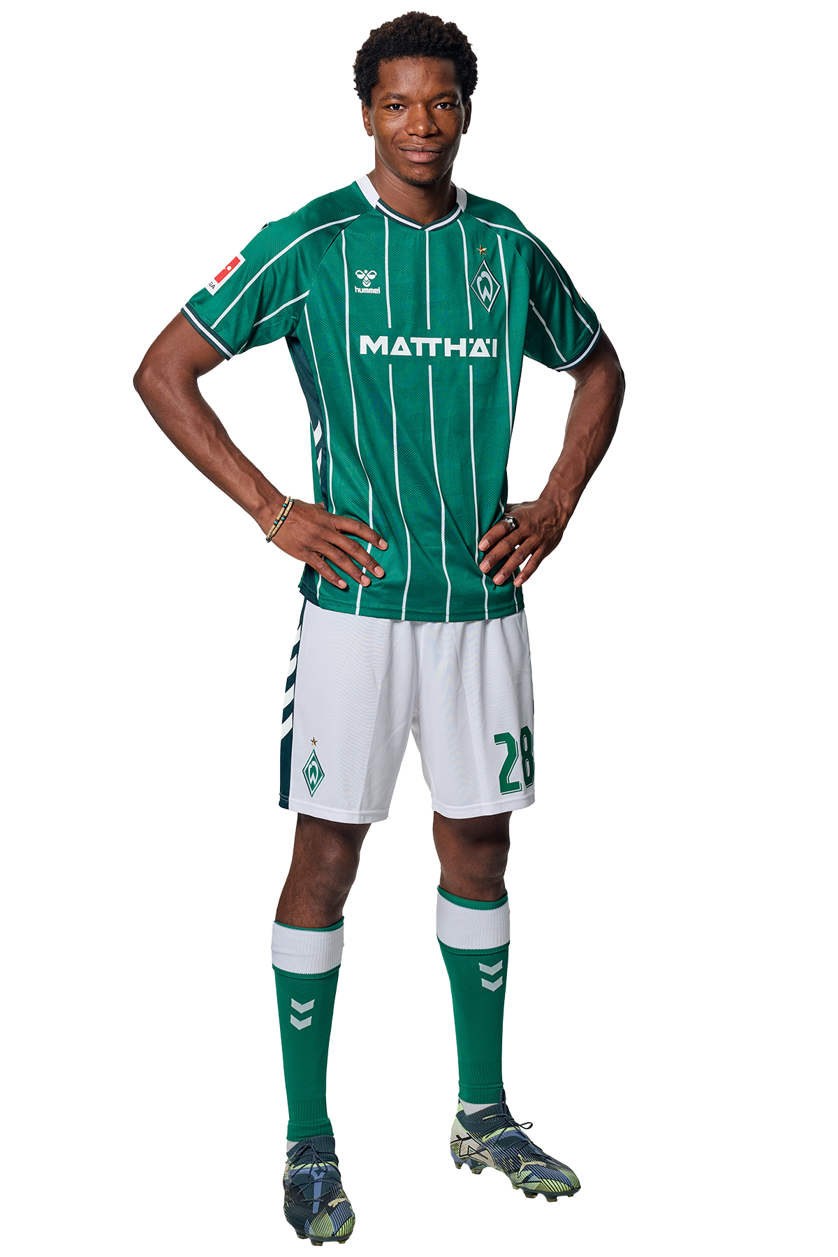 Skelly Alvero in einem grün-weiß gestreiften Trikot mit der Aufschrift „MATTHÄI“ auf der Vorderseite steht mit den Händen in den Hüften da und schaut nach vorne.