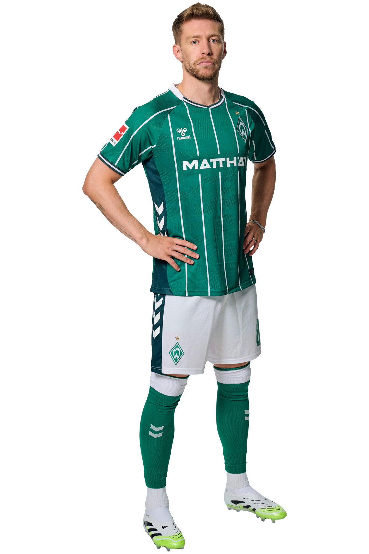 Mitchell Weiser im grün-weiß gestreiften Trikot mit Sponsorenlogos, der mit den Händen in den Hüften dasteht und nach vorne schaut.