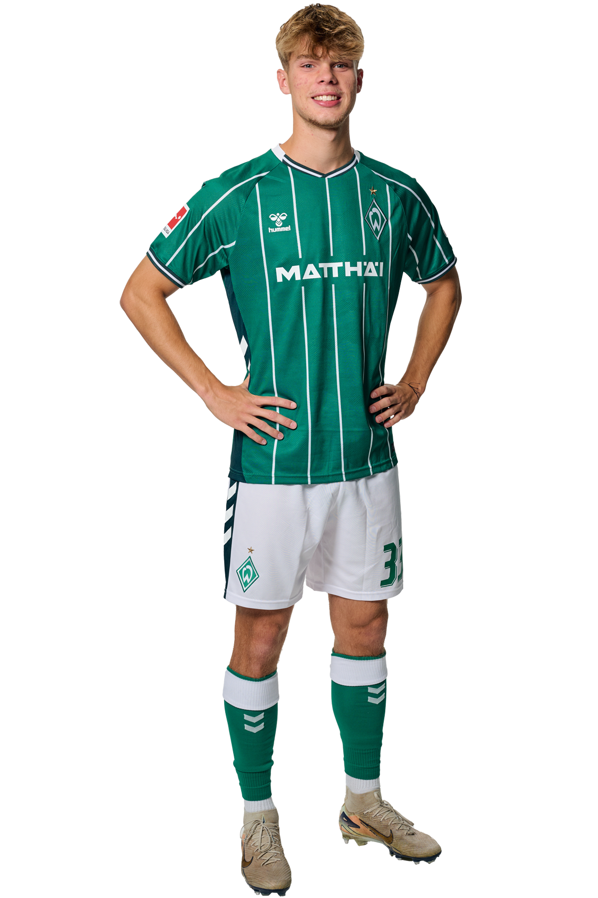 Mick Schmetgens in einem grün-weiß gestreiften Trikot mit der Aufschrift „MATTHÄI“ auf der Vorderseite steht mit den Händen in den Hüften da und schaut nach vorne.