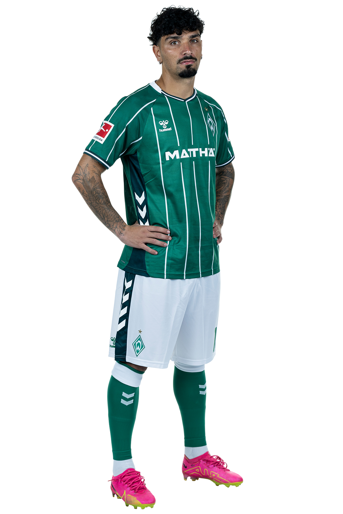Cameron Puertas in einem grün-weiß gestreiften Trikot mit der Aufschrift „MATTHÄI“ auf der Vorderseite steht mit den Händen in den Hüften da und schaut nach vorne.