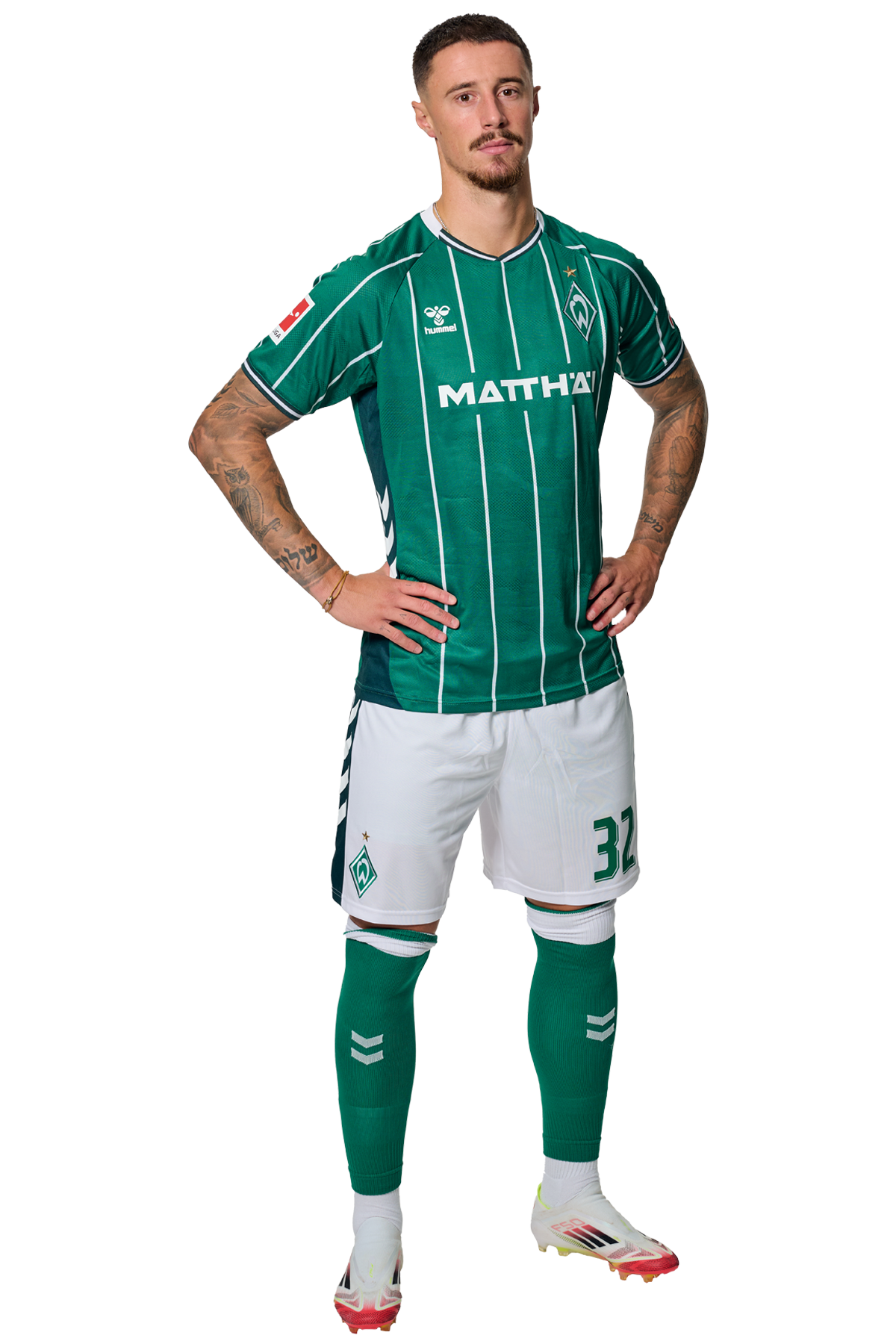 Marco Friedl in einem grün-weiß gestreiften Trikot mit der Aufschrift „MATTHÄI“ auf der Vorderseite steht mit den Händen in den Hüften da und schaut nach vorne.