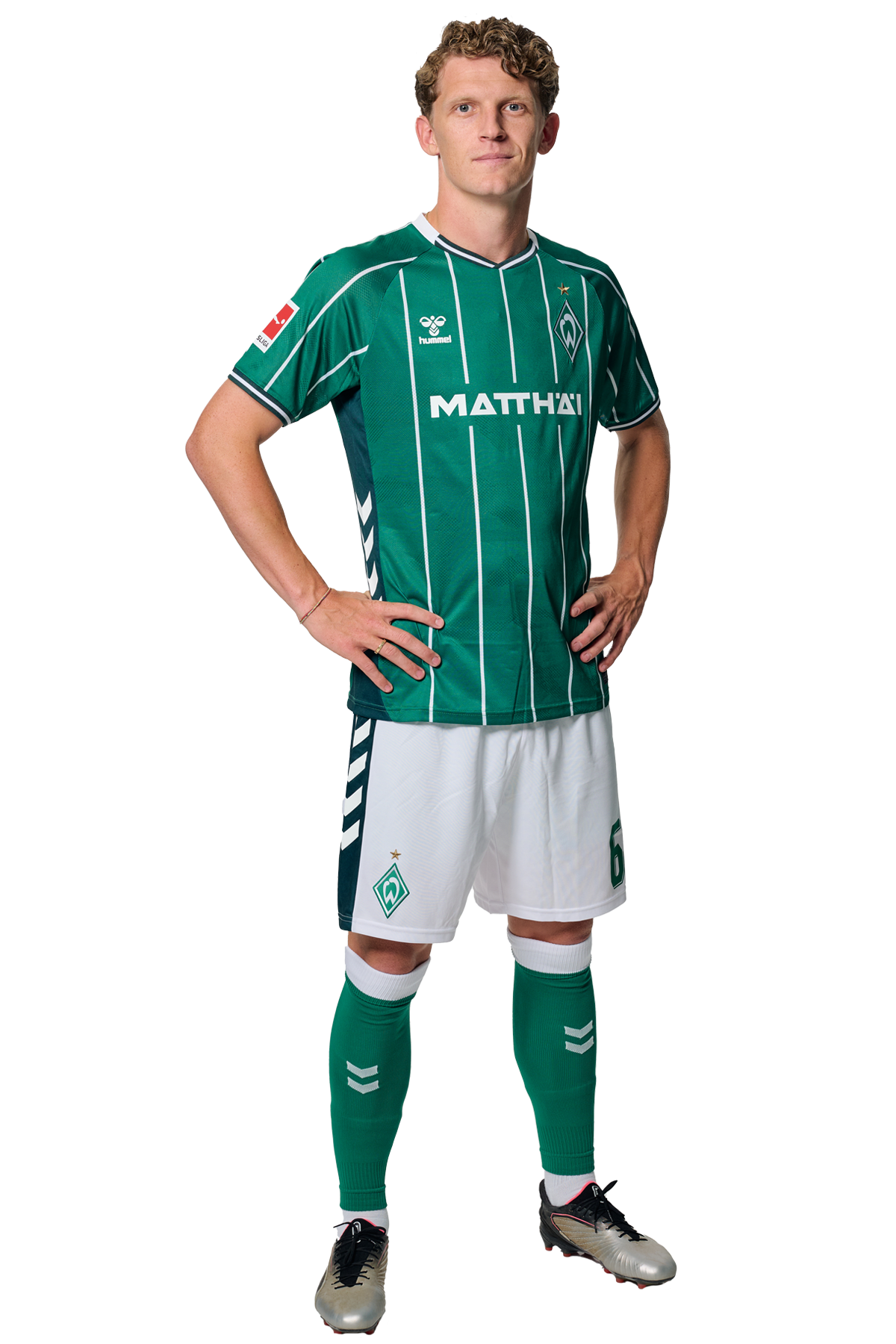 Jens Stage in einem grün-weiß gestreiften Trikot mit der Aufschrift „MATTHÄI“ auf der Vorderseite steht mit den Händen in den Hüften da und schaut nach vorne.