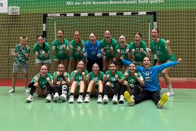 Eine Frauen-Handballmannschaft steht vor einem Tor und jubelt.
