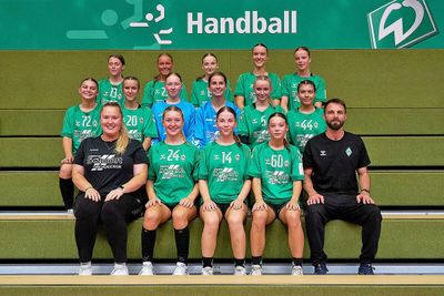 Spielerinnen & Trainerteam sitzen auf einer Bank.