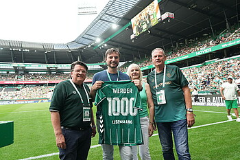 null Gruppenbild mit Trikotübergabe auf dem Rasen des Weserstadions vor vollen Tribünen in der Halbzeit.
