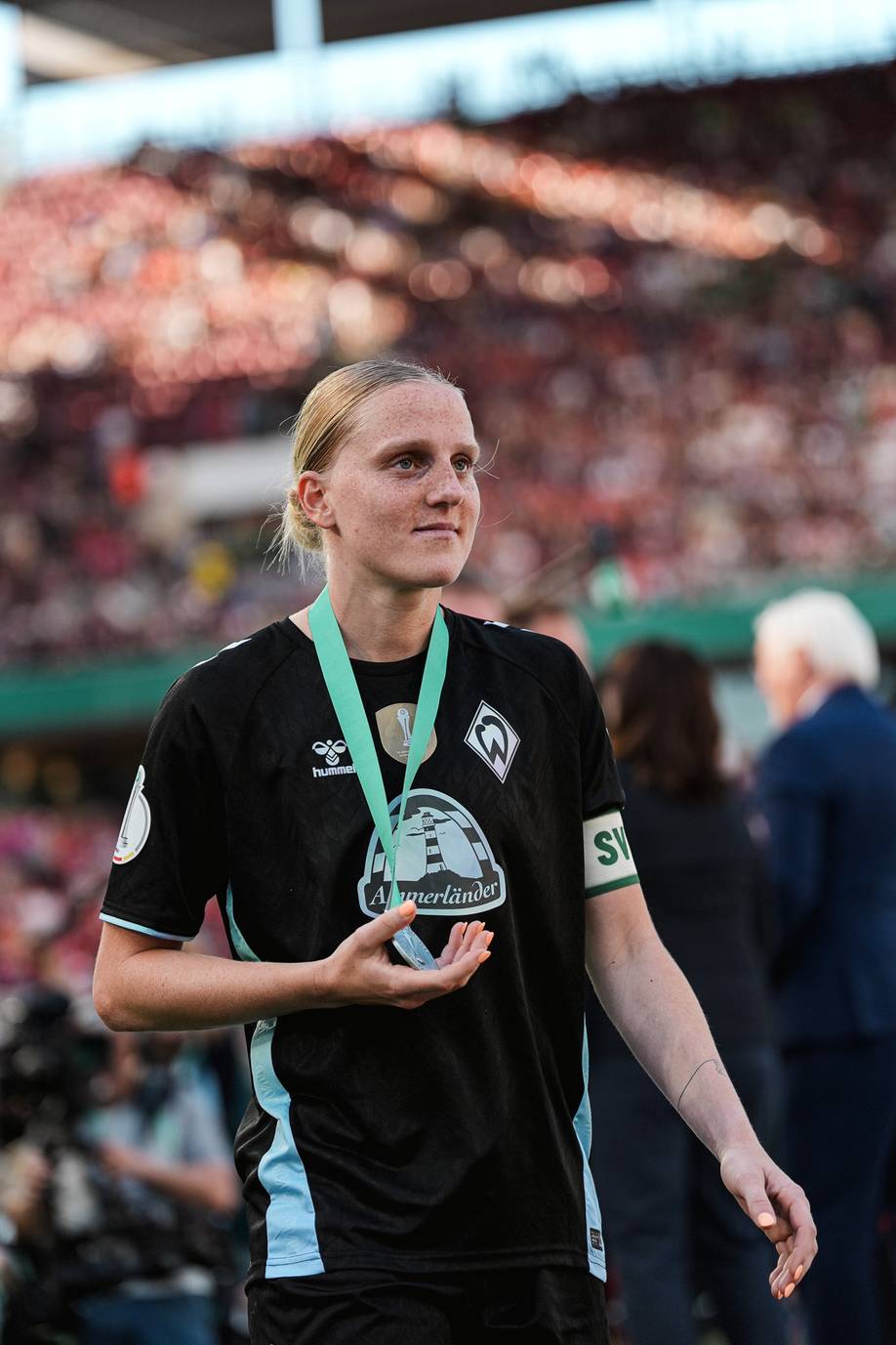 Lina Hausicke im schwarzen Pokal-Trikot hält ihre Silbermedaille in der Hand.
