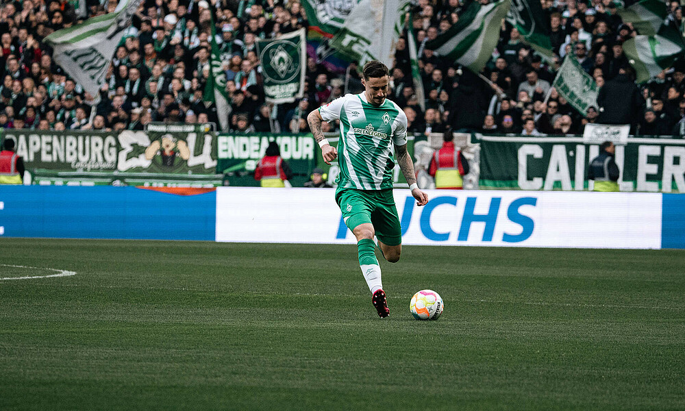 Marco Friedl hat seinen Ball am linken Fuß und spielt einen langen Ball. 