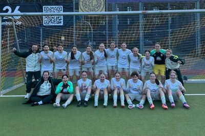 Ein Teamfoto der U17-Juniorinnen im weißen Auswärtstrikot. Sie jubeln in die Kamera.